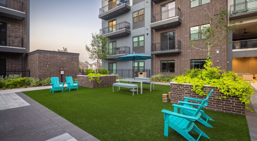 grass lawn with blue chairs and a building in the background