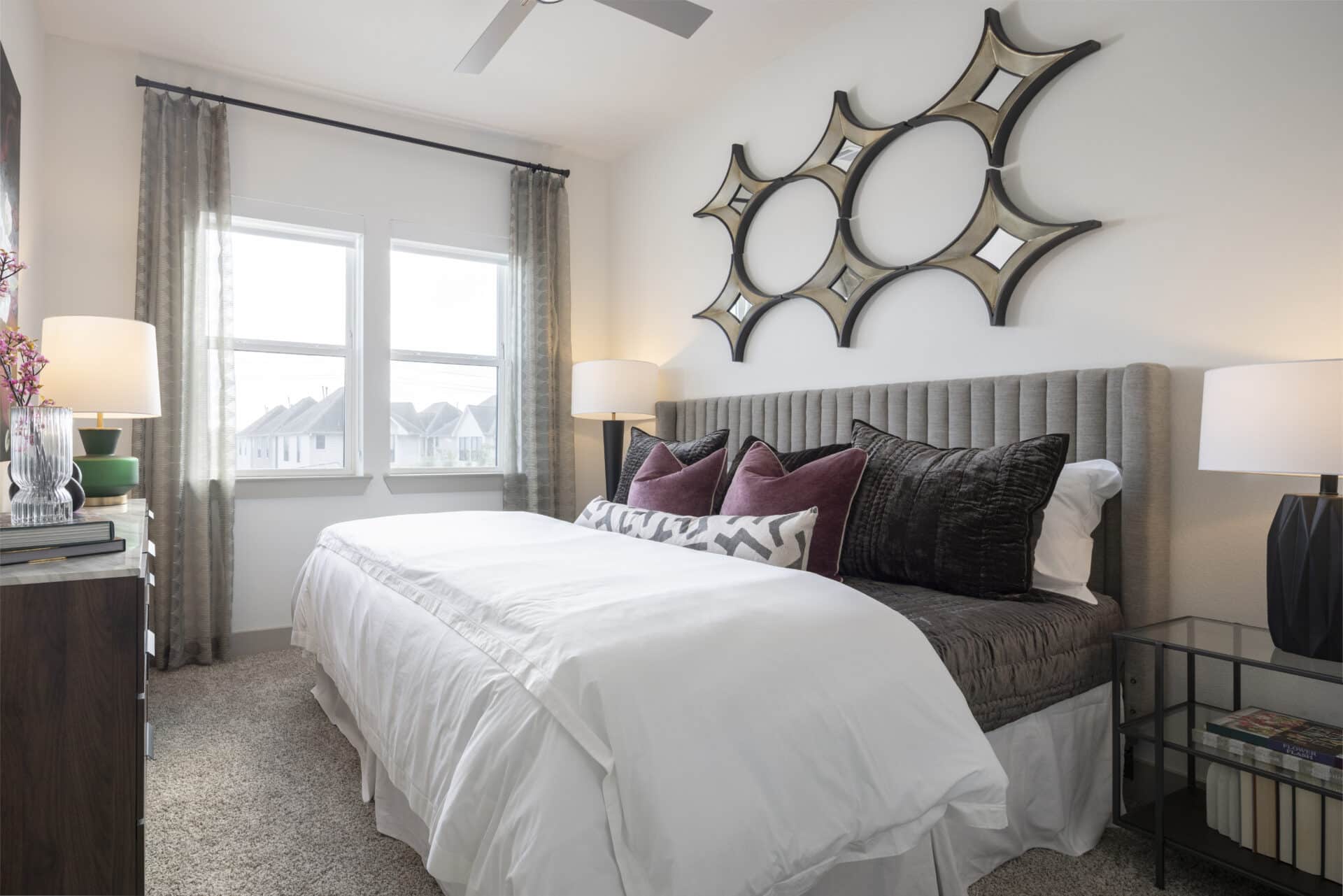 Bed in bedroom with maroon pillows and panoramic views out the floor to ceiling windows at Broadstone Emeline Heights in Houston, TX